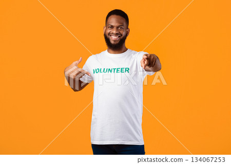 Happy black male volunteer activist pointing finger at his t-shirt and at camera posing on yellow studio background, inviting you to join volunteering career and work. You're next concept Happy black male volunteer activist pointing finger at his t-shirt and at camera posing on yellow studio background, inviting you to join volunteering career and work. You're next concept 134067253