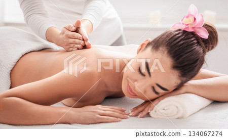 Beauty And Body Care. Young Asian Woman Relaxing During Massage Therapy Session In Spa Salon, Getting Wellness Treatment By Professional Masseur, Calm Lady Lying On Table With Closed Eyes, Closeup Beauty And Body Care. Young Asian Woman Relaxing During Massage Therapy Session In Spa Salon, Getting Wellness Treatment By Professional Masseur, Calm Lady Lying On Table With Closed Eyes, Closeup 134067274