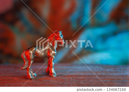 Small metallic pony scene, Miniature steel equine on surface with colorful lighting, Small metallic horse object illuminated with cinematic vibrant red and blue lights 134067288