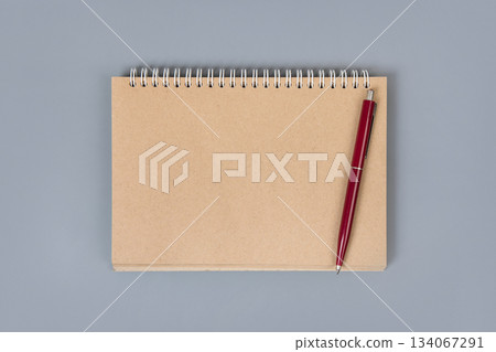 Opened blank notepad and pen on a grey background. Office desktop concept. Opened blank notepad and pen on a grey background. Office desktop concept. 134067291