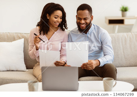 Planning Family Budget. Smiling black couple holding papers, calculating domestic bills and checking household expenses, reading documents or receipt from bank, talking about investment and finance Planning Family Budget. Smiling black couple holding papers, calculating domestic bills and checking household expenses, reading documents or receipt from bank, talking about investment and finance 134067299