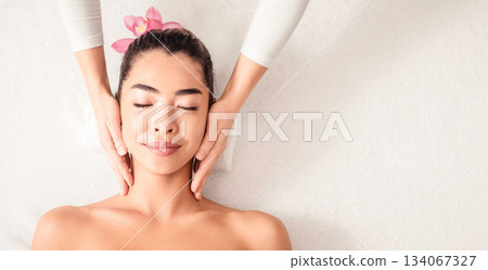 Beautiful asian woman enjoying face lifting massage, lying with closed eyes in spa salon, attractive young korean lady getting wellness treatment with professional masseur, top view with copy space Beautiful asian woman enjoying face lifting massage, lying with closed eyes in spa salon, attractive young korean lady getting wellness treatment with professional masseur, top view with copy space 134067327
