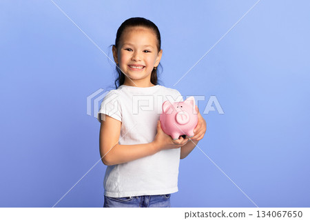 Personal Savings. Portrait of proud asian girl holding pink piggy bank, isolated on turquoise studio wall, copy space Personal Savings. Portrait of proud asian girl holding pink piggy bank, isolated on turquoise studio wall, copy space 134067650