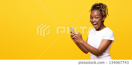 Excited black woman using mobile phone over yellow background, got new nice app, copy space Excited black woman using mobile phone over yellow background, got new nice app, copy space 134067743