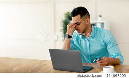 Millennial Arab entrepreneur having tired irritated eyes, overworking on laptop, exhausted from online job at office. Millennial guy employee feeling exhausted from looking at screen too long Millennial Arab entrepreneur having tired irritated eyes, overworking on laptop, exhausted from online job at office. Millennial guy employee feeling exhausted from looking at screen too long 134067905