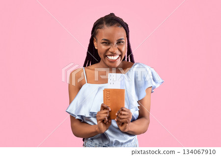 Overjoyed young black woman holding passport and plane tickets, going vacation overseas, traveling abroad over pink studio background. Tourism, summer holidays concept 134067910