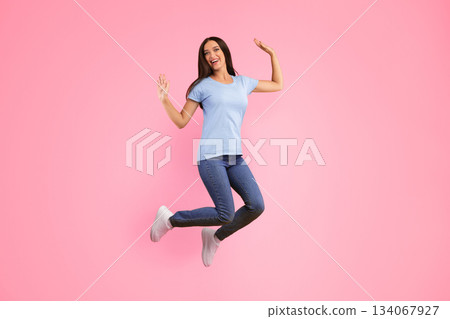 Expressing Joy And Happiness. Full length studio shot of active energetic young lady jumping isolated over yellow background. Excited female model celebrating success or victory, copy space 134067927