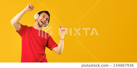 Life Is Good. Portrait of positive carefree guy listening to music with closed eyes, wearing wireless headset and dancing, relaxing and enjoying song isolated over blue studio background 134067936
