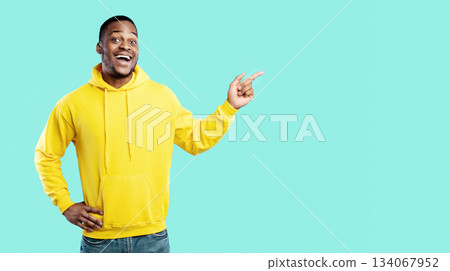 Look At This Offer. Excited Black Millennial Man Pointing Fingers Aside Showing Empty Space For Advertisement Text Standing Over Blue Background, Smiling To Camera. Studio Shot. Look There Concept Look At This Offer. Excited Black Millennial Man Pointing Fingers Aside Showing Empty Space For Advertisement Text Standing Over Blue Background, Smiling To Camera. Studio Shot. Look There Concept 134067952
