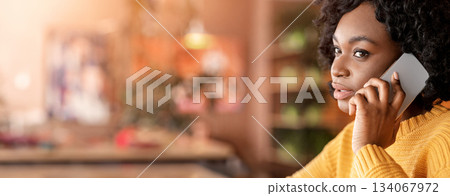 Close up profile photo of black woman talking on mobile phone, cafe interior, free space Close up profile photo of black woman talking on mobile phone, cafe interior, free space 134067972