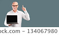 Useful Website. Middle-aged man pointing up and holding laptop with blank black screen over blue studio wall, mock up 134067980