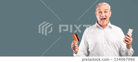Easy Payments. Happy adult man holding credit card and smartphone in his hands, free space Easy Payments. Happy adult man holding credit card and smartphone in his hands, free space 134067998