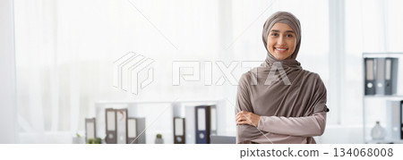 Business Career For Muslim Woman. Portrait Of Confident Arabic Businesswoman In Hijab Standing With Folded Arms Near Her Workplace In Office, Copy Space Business Career For Muslim Woman. Portrait Of Confident Arabic Businesswoman In Hijab Standing With Folded Arms Near Her Workplace In Office, Copy Space 134068008