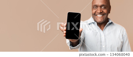 Cool mobile application. Smiling middle aged afro american man showing cellphone with blank screen Cool mobile application. Smiling middle aged afro american man showing cellphone with blank screen 134068040
