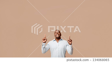 Look up there. Positive african middle aged man pointing up, looking at free space, orange studio background 134068065