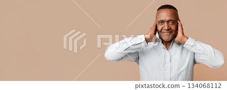 Hear no evil. Middle aged african man closing his ears, orange panorama background Hear no evil. Middle aged african man closing his ears, orange panorama background 134068112