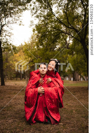 Interracial couple embracing in traditional Chinese wedding attire 134068150