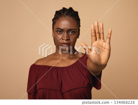 Young angry african american woman in casual outfit making the hand stop sign against beige studio background, closeup, copy space. Stop abuse, discrimination, violence concept Young angry african american woman in casual outfit making the hand stop sign against beige studio background, closeup, copy space. Stop abuse, discrimination, violence concept 134068228