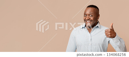 Happy middle aged african man gesturing thumb up, orange studio background Happy middle aged african man gesturing thumb up, orange studio background 134068256