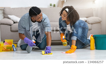 Household Concept. Young Black Couple Doing Spring Cleaning In Their Flat Together, Washing Floor And Smiling To Each Other, Free Space Household Concept. Young Black Couple Doing Spring Cleaning In Their Flat Together, Washing Floor And Smiling To Each Other, Free Space 134068257