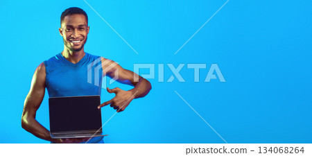 Stay Fit. Sporty Man Showing Laptop Blank Screen Recommending Online Workout During Coronavirus Quarantine Over Blue Studio Background. Mockup Stay Fit. Sporty Man Showing Laptop Blank Screen Recommending Online Workout During Coronavirus Quarantine Over Blue Studio Background. Mockup 134068264