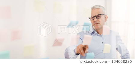 Project Planning. Serious Mature Businessman Reading Colorful Sticky Notes On Glass Visualisation Board In Office 134068280