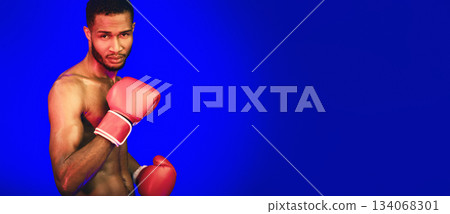 Boxing Sport. Determined Black Boxer Standing Ready To Fight Posing Over Blue Background. Studio Shot, Empty Space Boxing Sport. Determined Black Boxer Standing Ready To Fight Posing Over Blue Background. Studio Shot, Empty Space 134068301