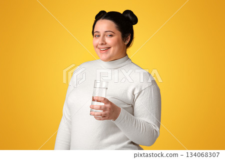 Hydration Concept. Young Positive Overweight Woman Posing With Glass Of Water In Hands Over Yellow BAckground, Free Space 134068307