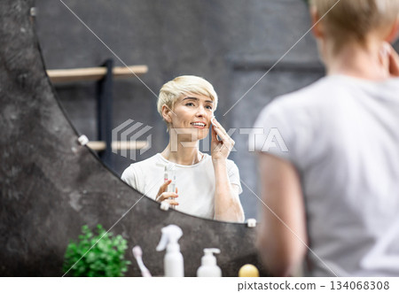 Skincare. Cheerful Lady Applying Tonic On Cotton Pad Refreshing Skin Standing In Bathroom At Home. Selective Focus, Empty Space Skincare. Cheerful Lady Applying Tonic On Cotton Pad Refreshing Skin Standing In Bathroom At Home. Selective Focus, Empty Space 134068308
