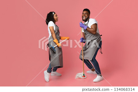 Joyful Housekeeping Concept. Portrait Of Cheerful African Couple Of Cleaners Having Fun During Chores Joyful Housekeeping Concept. Portrait Of Cheerful African Couple Of Cleaners Having Fun During Chores 134068314