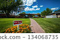 A brick house with a green lawn and a brick walkway leading to the front door is for sale. There are flowers planted along the edge of the walkway and a For Sale sign is visible in the foreground. A brick house with a green lawn and a brick walkway leading to the front door is for sale. There are flowers planted along the edge of the walkway and a For Sale sign is visible in the foreground. 134068735