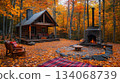 A rustic cabin nestled in a forest of colorful autumn leaves, accompanied by a stone fire pit. The warm atmosphere invites relaxation and enjoyment of the natural beauty during fall. A rustic cabin nestled in a forest of colorful autumn leaves, accompanied by a stone fire pit. The warm atmosphere invites relaxation and enjoyment of the natural beauty during fall. 134068739