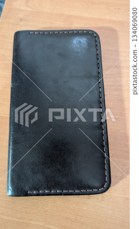 leather wallet scene, minimalist leather wallet resting on warm wooden surface under soft lighting leather wallet scene, minimalist leather wallet resting on warm wooden surface under soft lighting 134069080