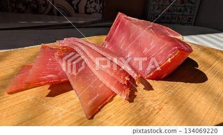 Elegant cured ham on rustic wooden surface with dramatic lighting 134069220