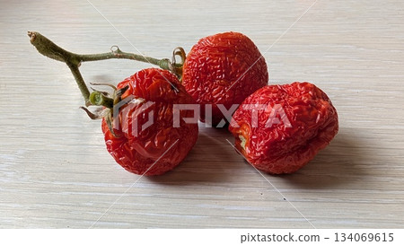 balanced composition of dried cherry tomatoes on pale background with natural shadows and warm red 134069615