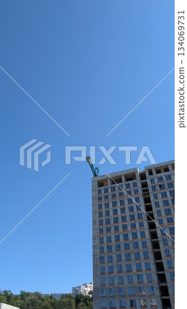 urban construction rise, city skyline with extending crane and building progress seen from below 134069731