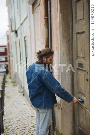 Person extends hand towards weathered door in quiet alley Person extends hand towards weathered door in quiet alley 134070219