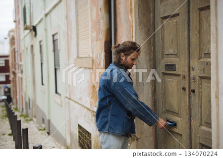 Casual individual uses key to open aged apartment door on city street Casual individual uses key to open aged apartment door on city street 134070224