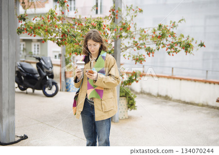 Woman in comfortable attire appreciating fresh morning air and electronics Woman in comfortable attire appreciating fresh morning air and electronics 134070244