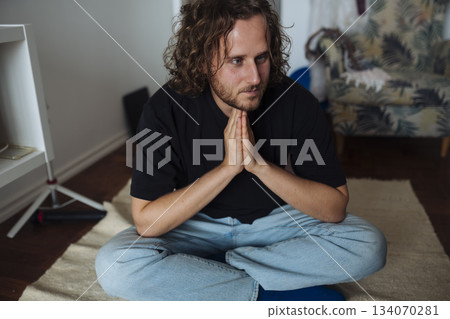 Peaceful individual seated with eyes closed in tranquil surroundings Peaceful individual seated with eyes closed in tranquil surroundings 134070281