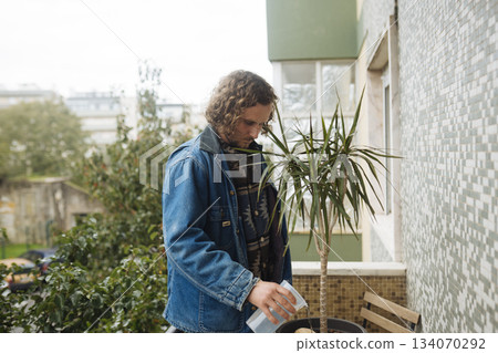 Individual watering potted plant during peaceful morning hours Individual watering potted plant during peaceful morning hours 134070292