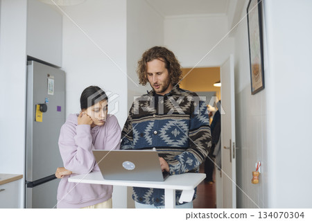 Father assisting young girl with homework in cozy kitchen setting 134070304