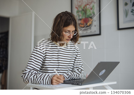 Young woman concentrating on research using digital and paper tools 134070306