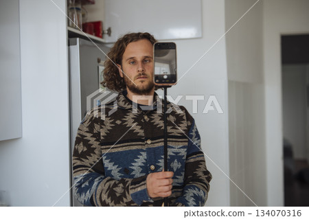 Person setting up filming device in small home space carefully Person setting up filming device in small home space carefully 134070316