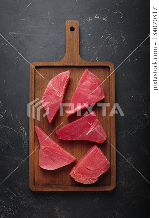 Raw tuna fish steaks fillet wooden cutting board black background healthy Raw tuna fish steaks fillet wooden cutting board black background healthy 134070317