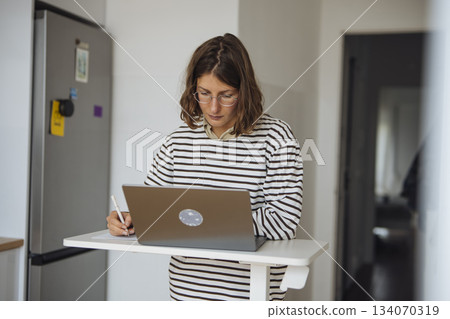 Businesswoman engaged with documents at modern standing desk setup Businesswoman engaged with documents at modern standing desk setup 134070319