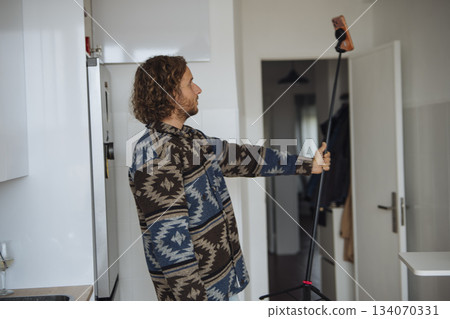 Individual using phone on stick to broadcast live moments in hallway Individual using phone on stick to broadcast live moments in hallway 134070331