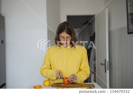 Young lady carefully carves fruit in cozy morning setting 134070332