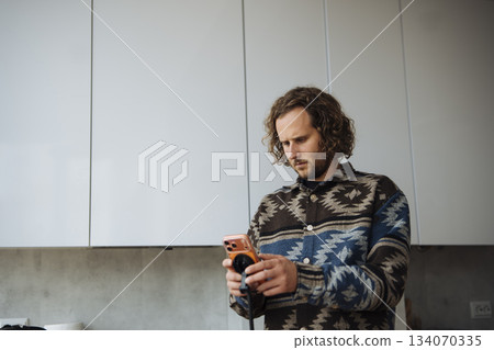 Man in kitchen opening bottle during friendly gathering evening Man in kitchen opening bottle during friendly gathering evening 134070335