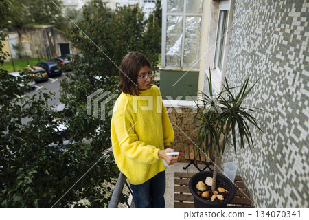 Peaceful female dressed vibrantly watches city from balcony Peaceful female dressed vibrantly watches city from balcony 134070341